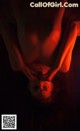 A naked woman laying on her back in the dark.