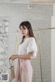 a woman standing in front of a white brick wall holding a handbag