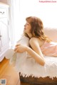 A woman laying on top of a couch next to a window.