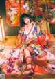 A woman in a colorful kimono sitting on the floor.