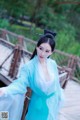 A woman in a blue dress standing on a wooden bridge.