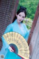 A woman in a blue dress holding a fan.