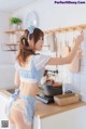 A woman in a blue and white dress standing in a kitchen.