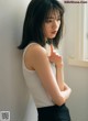 A woman leaning against a wall with her hand on her chin.