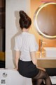 A woman sitting on a bathtub in front of a mirror.