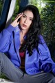 A woman in a blue jacket sitting on a window sill.