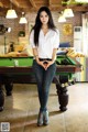 A woman standing in front of a pool table.