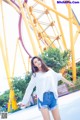 A woman standing in front of a roller coaster.