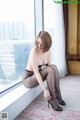 A woman sitting on a window sill wearing black stockings.