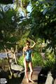 A woman in a bathing suit standing on a wooden walkway.