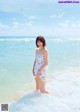 A woman in a white dress standing in the ocean.