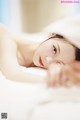 A woman laying on top of a bed under a blanket.