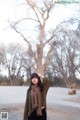 A woman standing in front of a large tree.