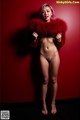 A naked woman in a red fur coat posing for a picture.