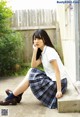 A young woman in a school uniform sitting on a ledge.