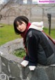 A woman sitting on top of a stone wall.