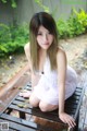 A woman in a white dress sitting on a wooden bench.