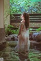 A woman in a white dress standing in a pool of water.