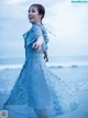 A woman in a blue dress standing on the beach.