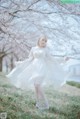 A woman in a white dress standing in a field of flowers.