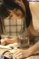 A naked woman sitting at a table with a bottle of water.