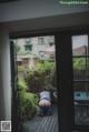 A person sitting on a wooden deck looking out a window.