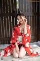 A woman in a red kimono sitting on the ground.