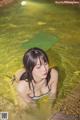 A woman in a bikini laying in a pool of water.