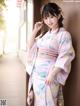 A woman in a pink kimono leaning against a wall.